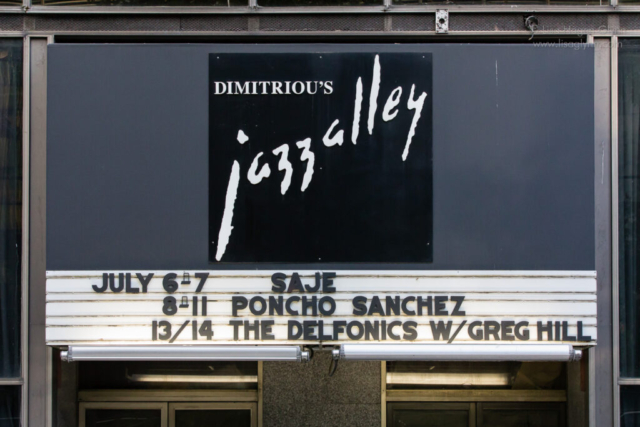 A sign outside Jazz Alley lists upcoming acts:  säje, Poncho Sanchez, and The Delfonics with Greg Hill