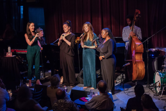 Erin Bentlage, Sara Gazarek, Amanda Taylor, & Johnaye Kendrick are accompanied by Dawn Clement and Ben Williams. A club audience appears in the foreground.
