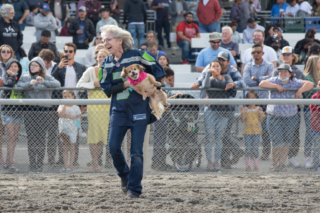 A person in a Seattle Seahawks jersey carries a wiener wannabe with a large smile onto the track