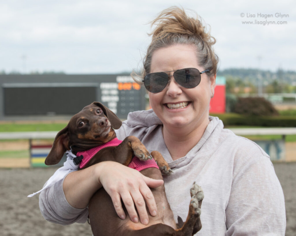 A smiling person holds a wiener dog like a baby