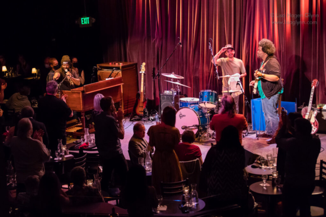 Delvon Lamarr Organ Trio stands onstage, and the audience stands to applaud.