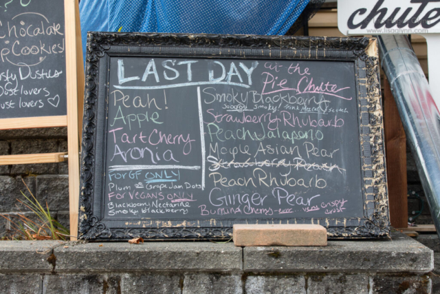 A chalkboard lists the varieties of pie available, and notes that today is the last day at the pie chute.