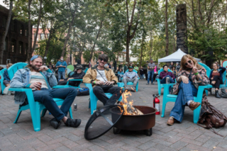 Smokey Brights sit beside a fire pit in Occidental Square before the show