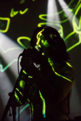 Kelly Lee Owens with green lights from a projector across her face