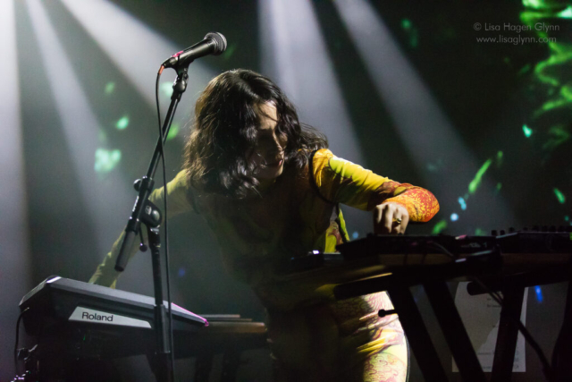 Kelly Lee Owens turns to the left while turning a knob