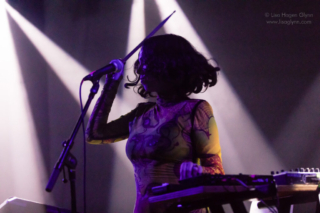 Kelly Lee Owens holds a drumstick above her head
