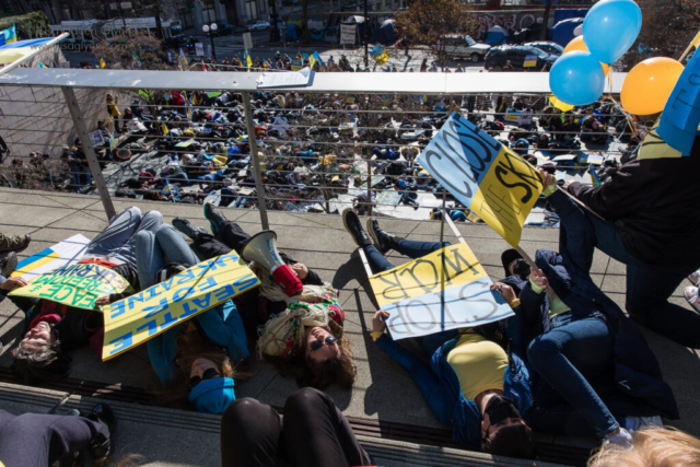 March organizers lie on the ground in response to an air-raid siren, during a "flash mob" at the start of the march.