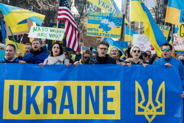 Marchers shout while carrying a banner that reads, "Ukraine."