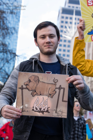 A marcher carries a political cartoon.