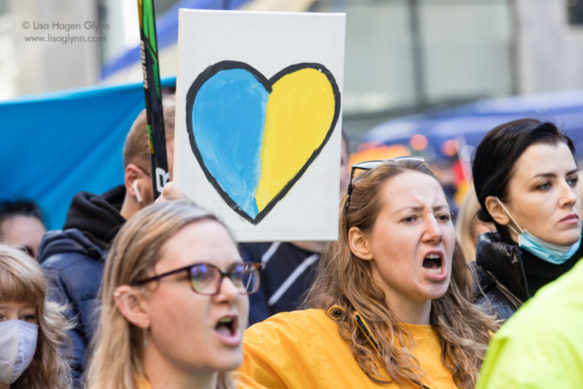 Marchers yell while carrying a sign depicts a blue and yellow heart.