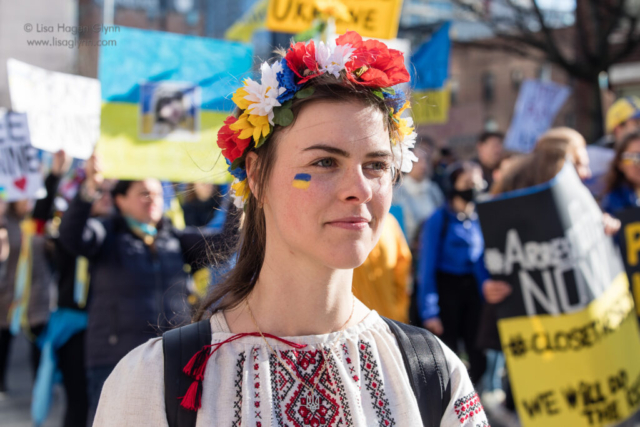Oksana wears a floral headdress and blue and yellow face paint.
