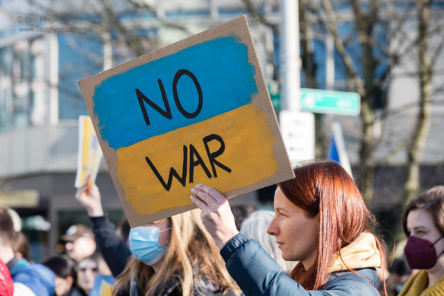 A sign reads, "No war" in yellow and blue