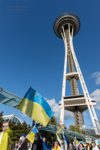 Marchers wave signs and Ukrainian flags, with the Space Needle rising behind