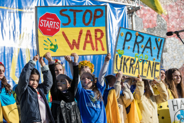Children hold signs that read, "Stop war" and "Pray for Ukraine"