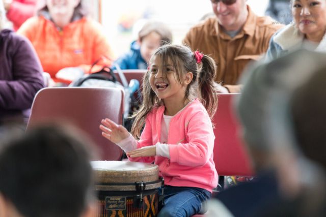A child smiles while drumming