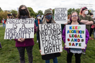 Three protesters hold abortion-rights signs