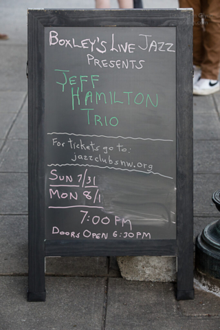 Folding sign outside Boxley's advertising the Jeff Hamilton Trio in green and pink lettering.