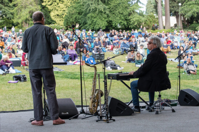 Hans Teuber and Jovino Santos Neto perform in Volunteer Park, with the audience behind